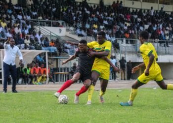 Footballers compete during a Nigerian domestic league match in a crowded stadium