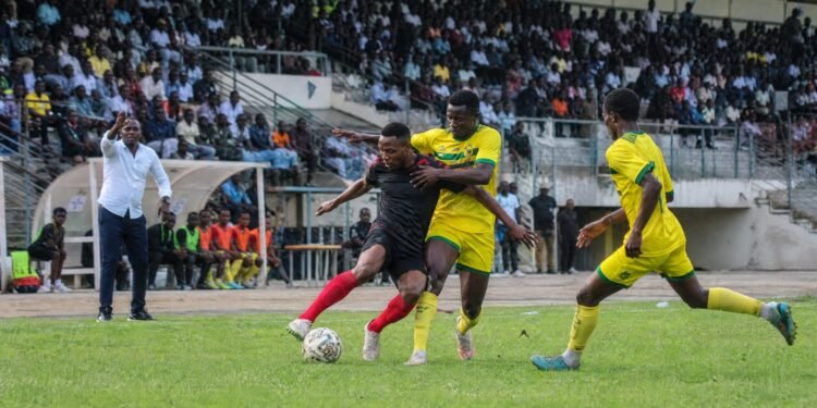 Footballers compete during a Nigerian domestic league match in a crowded stadium