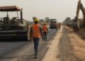 Construction workers in helmets and safety vests at a Nigerian highway construction site
