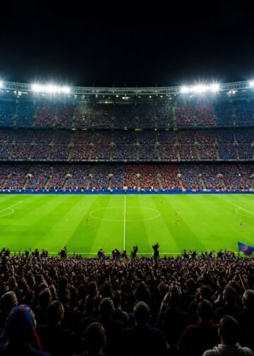 Packed football stadium at night with floodlights and fans in blue and red