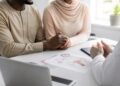 Couple holding hands hopefully in a bright fertility clinic consultation room