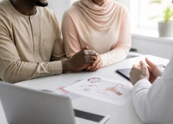 Couple holding hands hopefully in a bright fertility clinic consultation room