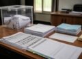 Ballot box and document checklists arranged on a desk in an election office