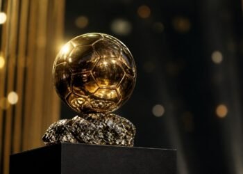 Golden football trophy on a plinth under stage lights at an awards ceremony