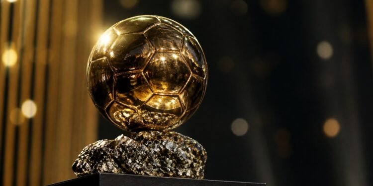 Golden football trophy on a plinth under stage lights at an awards ceremony