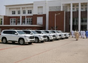 Row of brand-new white luxury SUVs parked at a political party secretariat in Nigeria