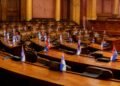 Legislative chamber desks with documents and national flags in soft light