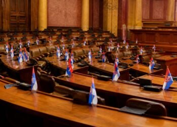 Legislative chamber desks with documents and national flags in soft light