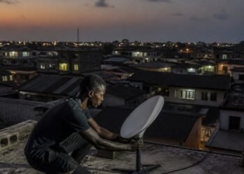 Small satellite internet dish mounted on a rooftop in a Nigerian neighbourhood at dusk