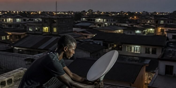 Small satellite internet dish mounted on a rooftop in a Nigerian neighbourhood at dusk