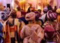 Guests in colourful aso-oke outfits celebrating at a traditional Nigerian wedding venue
