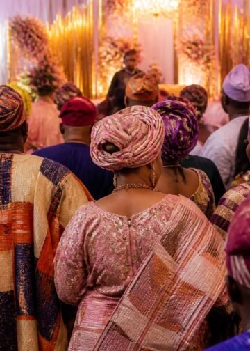 Guests in colourful aso-oke outfits celebrating at a traditional Nigerian wedding venue